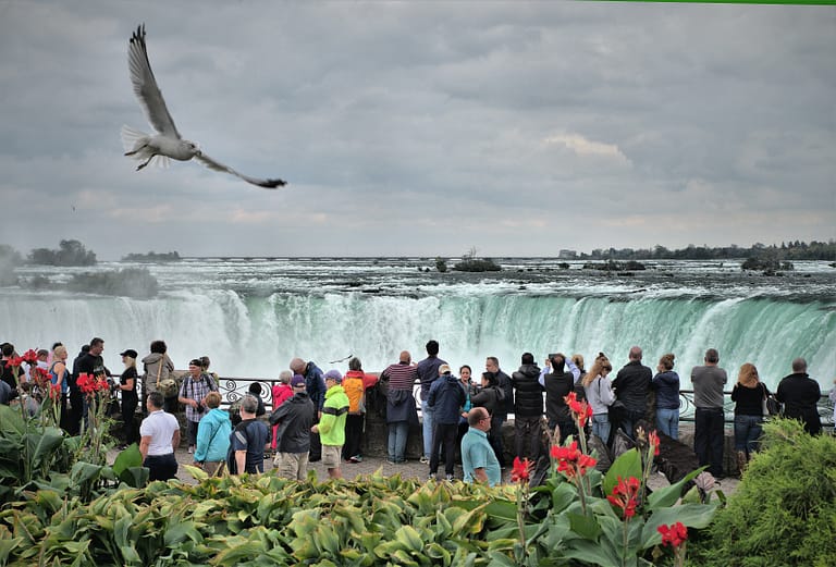 a group of tourists visiting Canada standing in front of Niagara falls